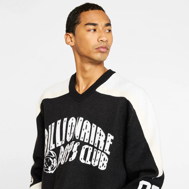 Person wearing a black and white sweater with 'Billionaire Boys Club' text on a plain background